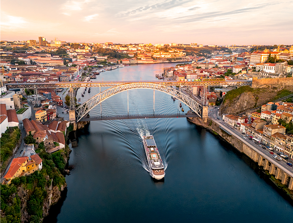 Crucero fluvial navegando por el río Duero junto al puente Don Luis I en Oporto, Portugal.